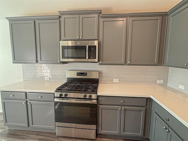 kitchen with stainless steel appliances, dark wood-type flooring, tasteful backsplash, and gray cabinets