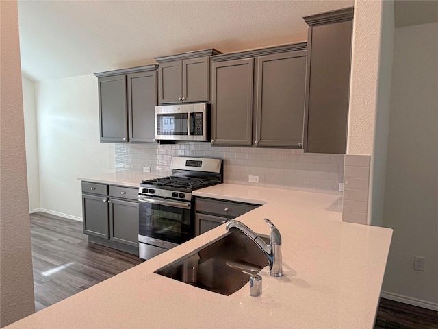 kitchen with dark hardwood / wood-style floors, stainless steel appliances, tasteful backsplash, gray cabinets, and sink