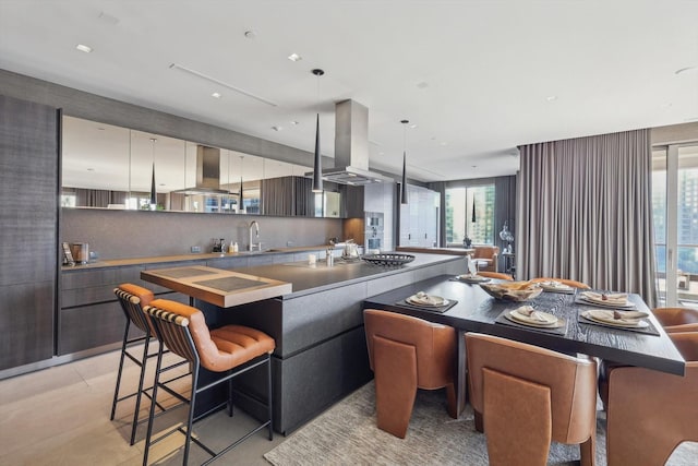 kitchen with light tile patterned floors, island exhaust hood, decorative light fixtures, range hood, and sink