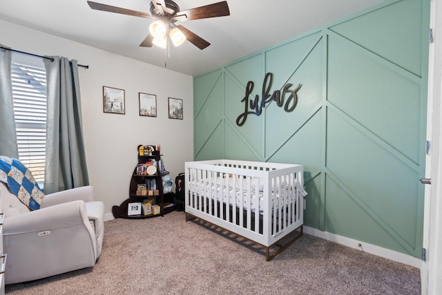 carpeted bedroom featuring a nursery area and ceiling fan