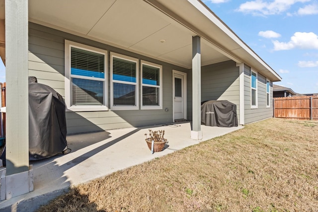 view of exterior entry with a lawn and a patio area