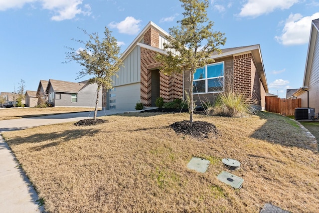 view of front of home with central AC unit, a front yard, and a garage