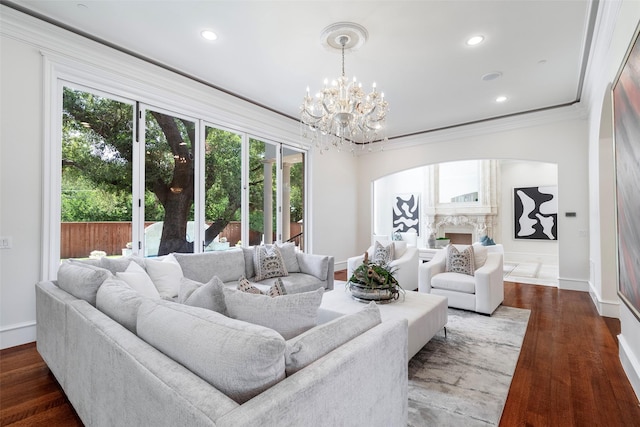 living room featuring a premium fireplace, dark hardwood / wood-style flooring, crown molding, and a chandelier