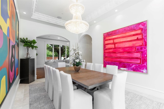 tiled dining area with an inviting chandelier, a tray ceiling, and crown molding