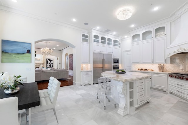 kitchen with custom exhaust hood, built in appliances, decorative backsplash, a kitchen island, and white cabinets