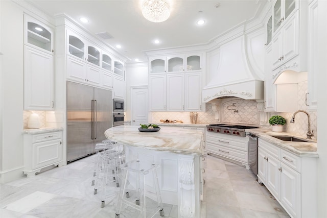 kitchen with built in appliances, white cabinets, and light stone countertops