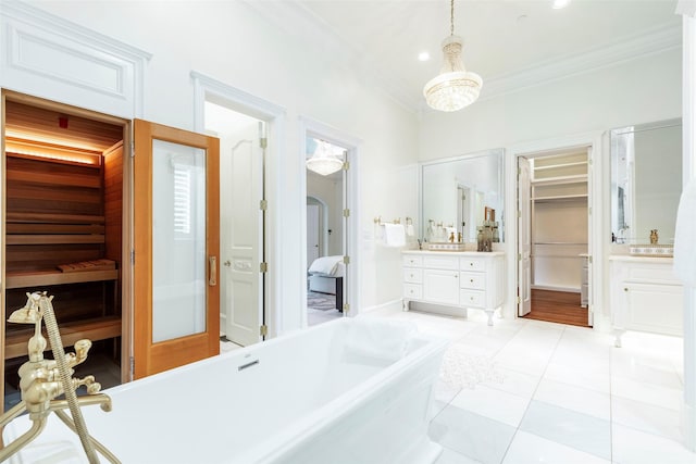 bathroom featuring a washtub, tile patterned floors, vanity, ornamental molding, and an inviting chandelier