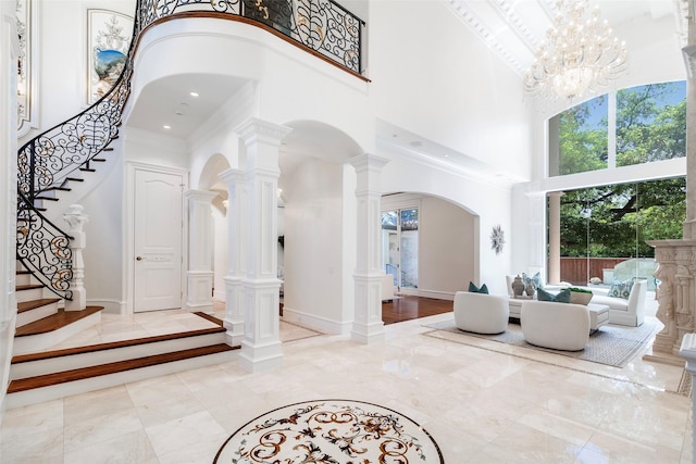 foyer featuring a towering ceiling, an inviting chandelier, and crown molding