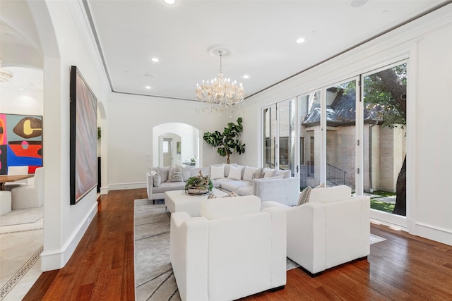 living room with ornamental molding, dark wood-type flooring, and an inviting chandelier