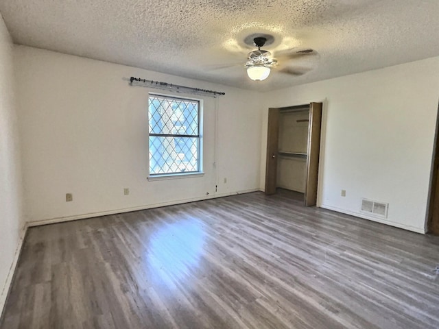 unfurnished bedroom with dark wood-type flooring, a textured ceiling, and ceiling fan