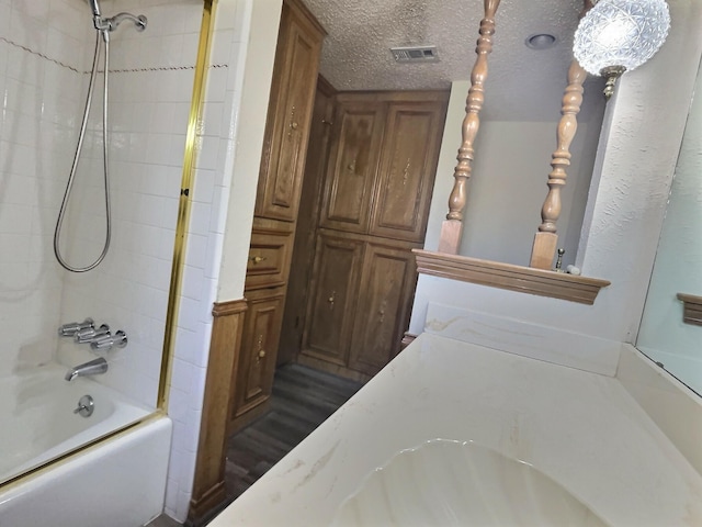 bathroom with hardwood / wood-style flooring, a textured ceiling, shower / bathtub combination, and sink