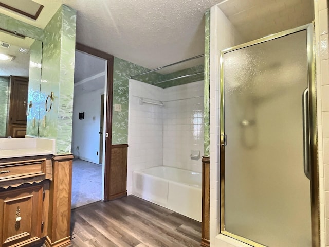 bathroom with a textured ceiling, plus walk in shower, vanity, and wood-type flooring