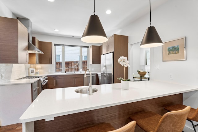 kitchen featuring decorative light fixtures, kitchen peninsula, appliances with stainless steel finishes, and sink