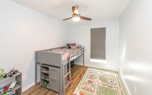 bedroom featuring baseboards, wood finished floors, and a ceiling fan