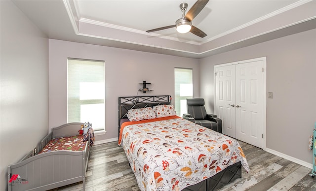 bedroom with a tray ceiling, a closet, and wood finished floors