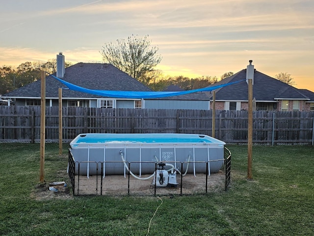 pool at dusk featuring a fenced in pool, a lawn, and fence