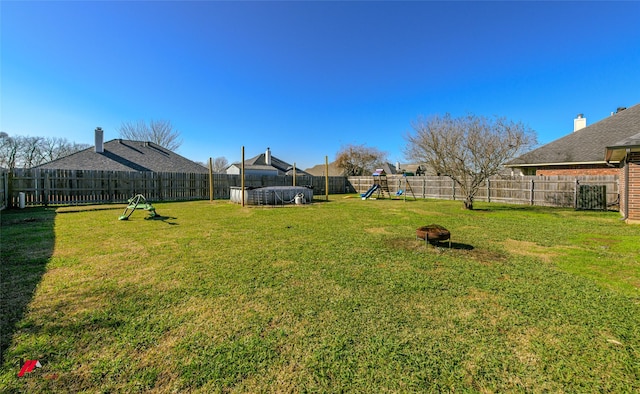 view of yard featuring a playground, a fenced backyard, and a trampoline