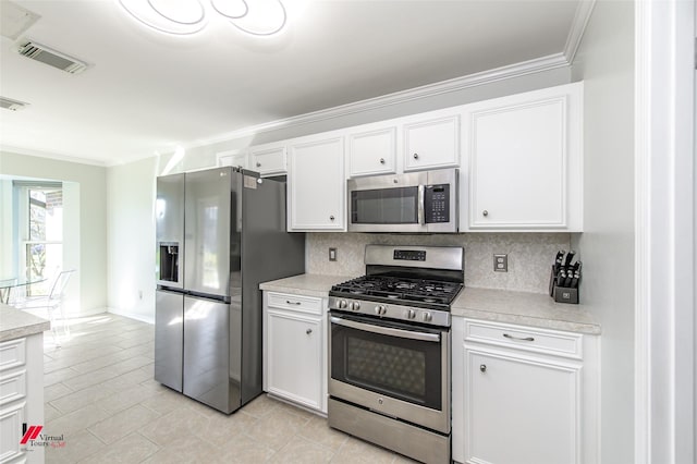 kitchen with stainless steel appliances, white cabinetry, light tile patterned flooring, tasteful backsplash, and crown molding