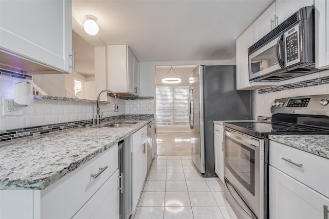 kitchen with appliances with stainless steel finishes, white cabinetry, sink, and light tile patterned floors