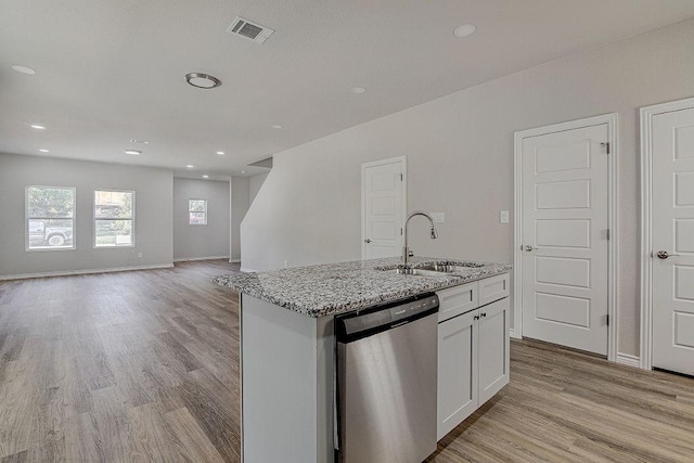 kitchen with light stone countertops, stainless steel dishwasher, a center island with sink, white cabinetry, and sink