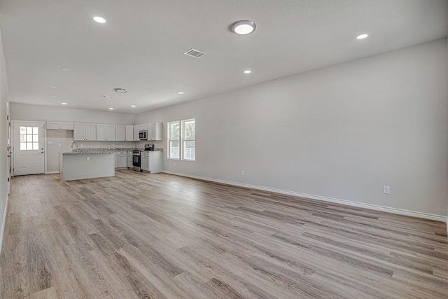 unfurnished living room with a healthy amount of sunlight, light wood-type flooring, and sink