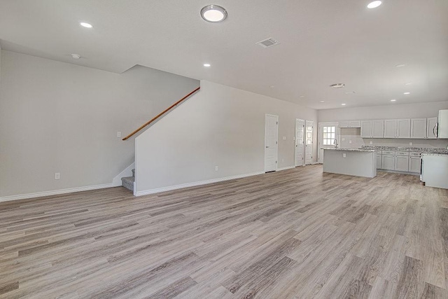 unfurnished living room with sink and light hardwood / wood-style flooring