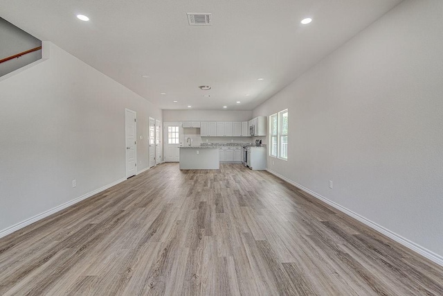 unfurnished living room featuring sink and light hardwood / wood-style flooring