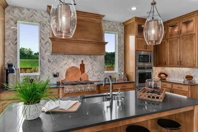 kitchen with custom exhaust hood, stainless steel appliances, hanging light fixtures, sink, and backsplash