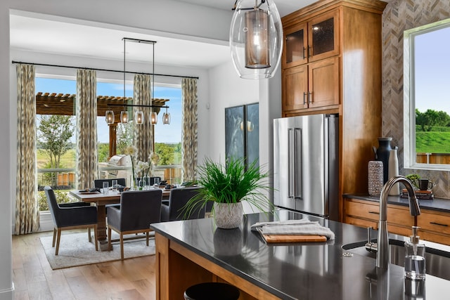 kitchen with sink, hanging light fixtures, light wood-type flooring, and high end refrigerator