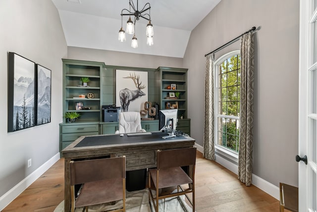 office featuring a notable chandelier, light wood-type flooring, and vaulted ceiling