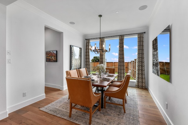 dining space with ornamental molding, a healthy amount of sunlight, an inviting chandelier, and hardwood / wood-style flooring