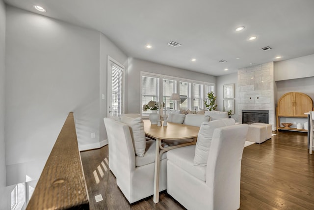 dining room with dark wood-type flooring and a tile fireplace