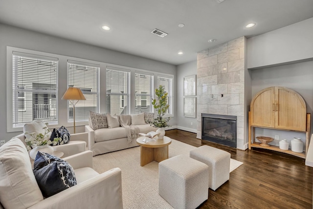 living room with a tile fireplace and dark hardwood / wood-style floors