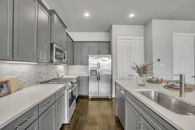 kitchen featuring sink, gray cabinets, light stone countertops, dark hardwood / wood-style flooring, and appliances with stainless steel finishes