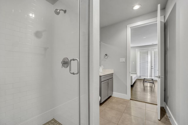 bathroom with a shower with door, vanity, and tile patterned floors