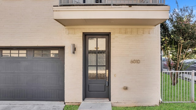 entrance to property with a balcony, a yard, and a garage