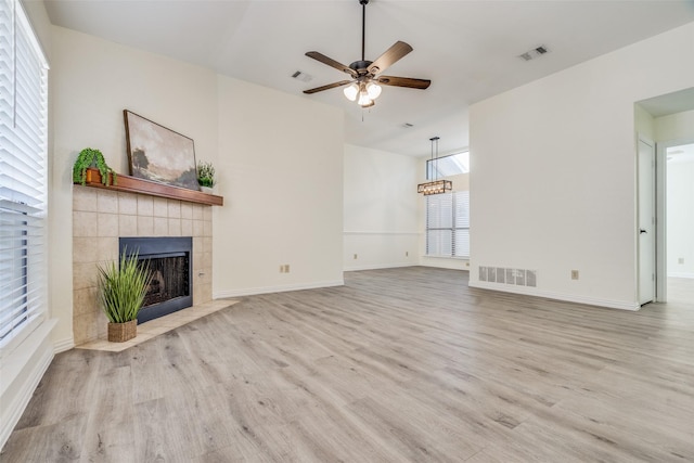 unfurnished living room with light wood-type flooring, a tiled fireplace, and ceiling fan