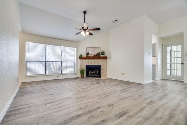 unfurnished living room with a tiled fireplace, ceiling fan, light hardwood / wood-style floors, and lofted ceiling