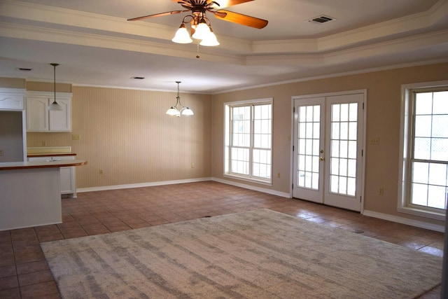 interior space with french doors, crown molding, ceiling fan with notable chandelier, and a tray ceiling