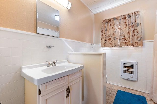 bathroom with heating unit, toilet, vanity, tile walls, and ornamental molding