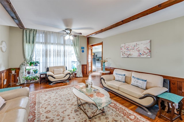 living room featuring ceiling fan, beamed ceiling, and wood-type flooring