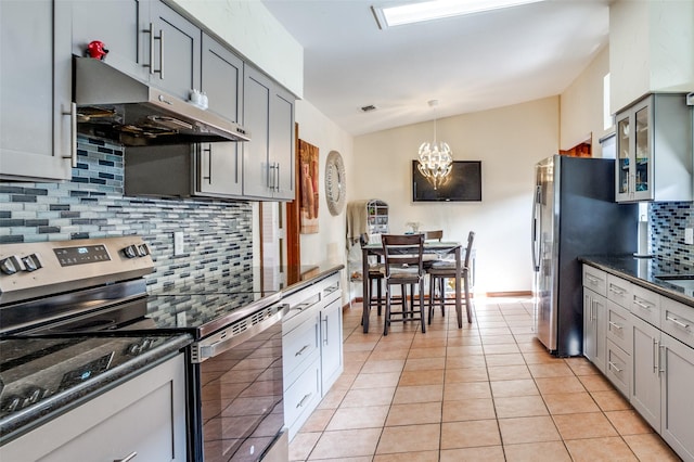 kitchen featuring vaulted ceiling, light tile patterned floors, gray cabinets, backsplash, and appliances with stainless steel finishes