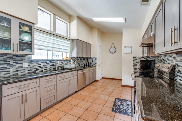 kitchen with appliances with stainless steel finishes, dark stone counters, tasteful backsplash, and light tile patterned floors