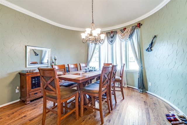 dining area with a notable chandelier, hardwood / wood-style floors, and crown molding