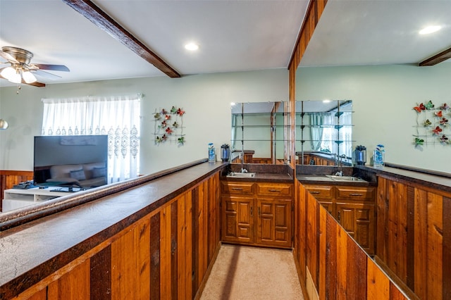 kitchen featuring sink, light carpet, ceiling fan, and beamed ceiling