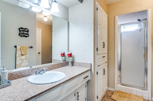 bathroom featuring a shower with door and vanity