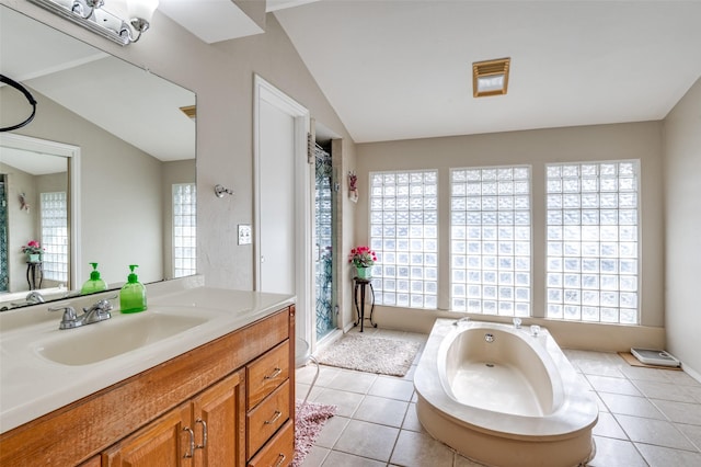 bathroom with lofted ceiling, tile patterned floors, a tub to relax in, and vanity