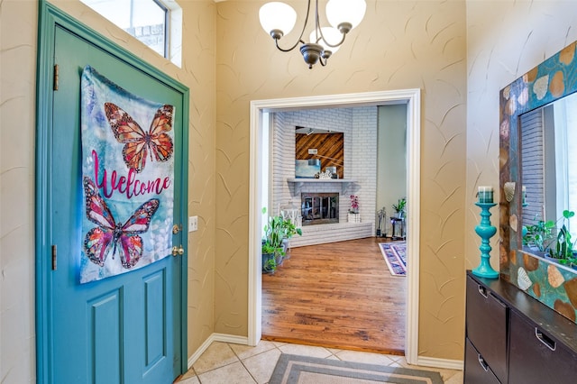 foyer entrance featuring a fireplace, light tile patterned floors, and a chandelier