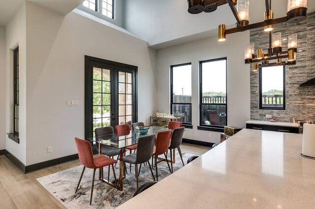 dining room with french doors, a high ceiling, a healthy amount of sunlight, and light hardwood / wood-style flooring