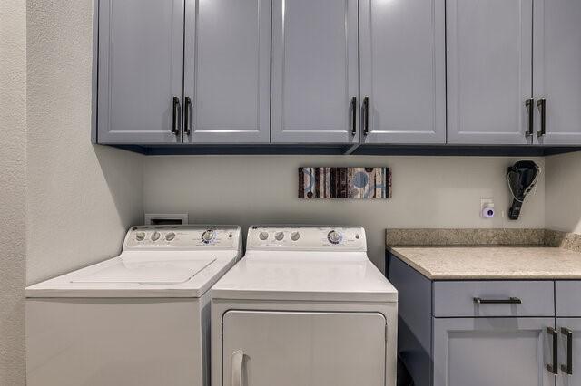 clothes washing area featuring washer and dryer and cabinets